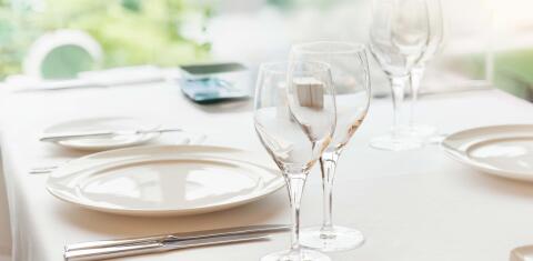 Elegant gedeckter Tisch mit weißen Tellern, Besteck und Gläsern.