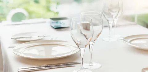 Elegant gedeckter Tisch mit weißen Tellern, Besteck und Gläsern.
