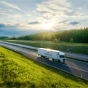 Ein Bad Pyrmonter LKW fährt auf einer Autobahn durch grüne Landschaft bei Sonnenuntergang.