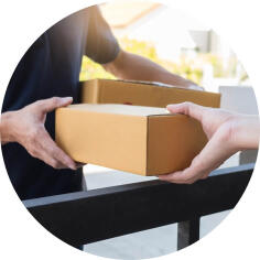 Übergabe eines Pakets zwischen zwei Personen an einem Zaun.