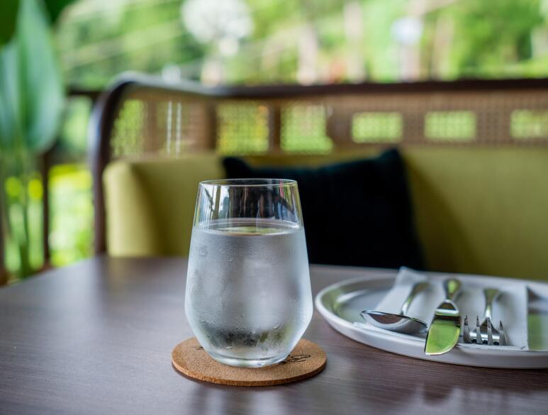 Ein Glas frisches Wasser auf einem gedeckten Tisch mit Teller und Besteck.