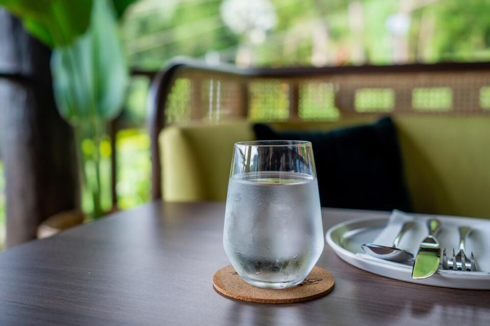 Glas mit frischem Wasser auf einem gedeckten Tisch in gemütlichem Ambiente.