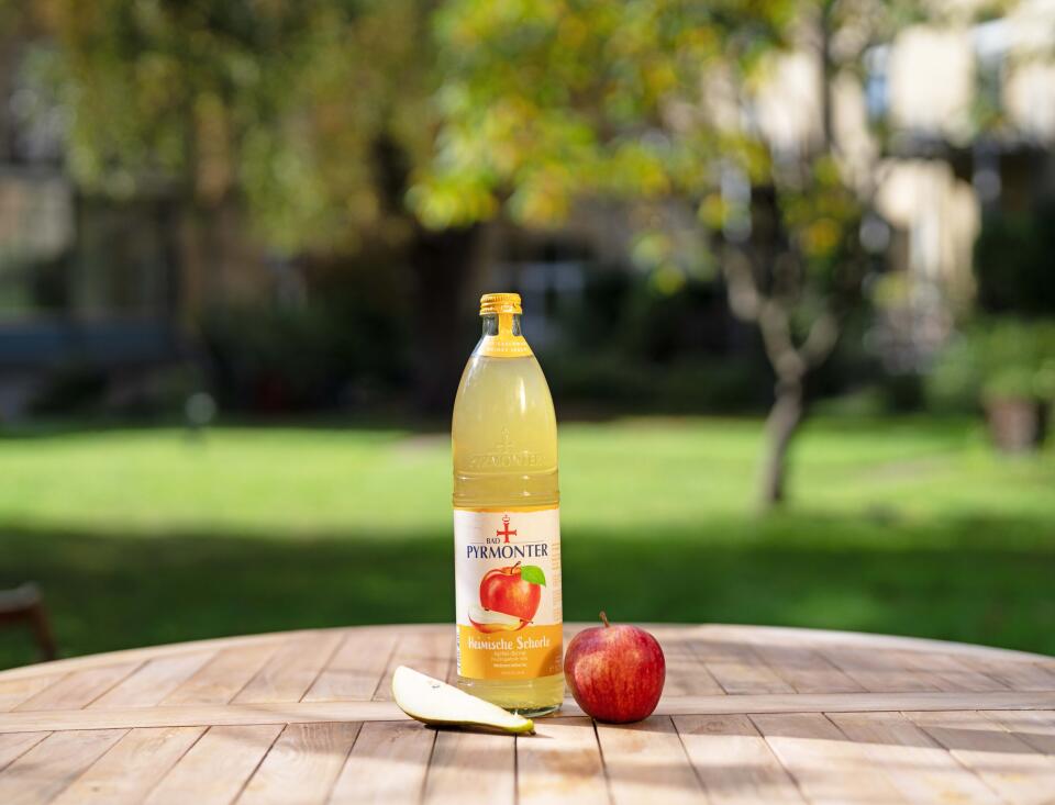 Bad Pyrmonter Heimische Schorle Apfel Birne auf einem Holztisch vor Naturhintergrund.