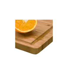 Bambus-Schneidebrett mit Saftrille, darauf eine halbierte Orange und ausgelaufener Saft.