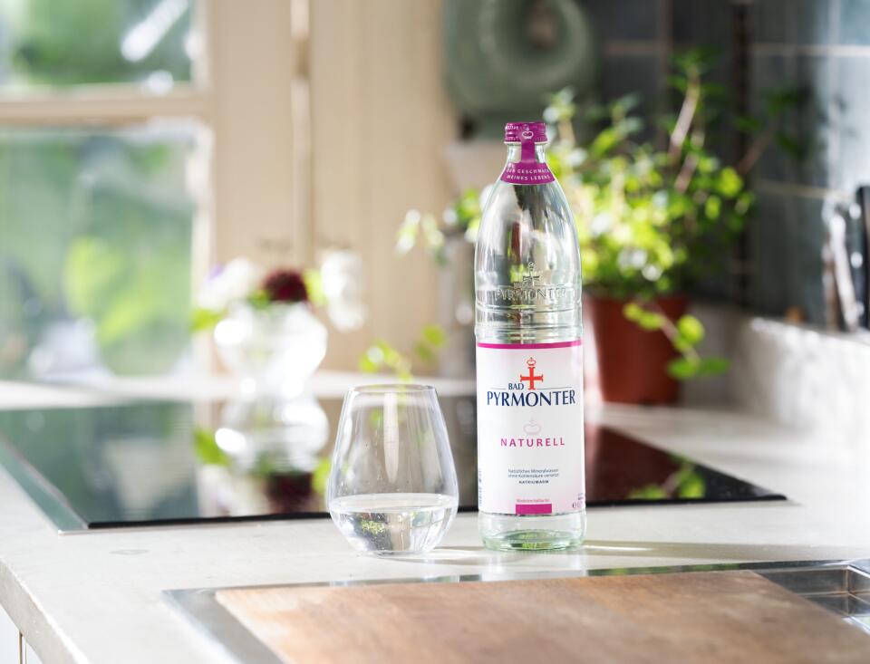 Bad Pyrmonter Mineralwasser Naturell mit Glas auf einer modernen Küchenzeile.