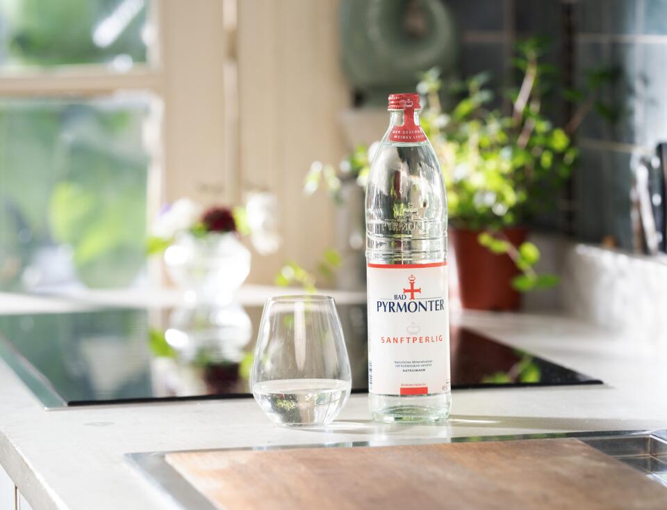 Bad Pyrmonter Mineralwasser Sanftperlig mit Glas auf einer modernen Küchenzeile.