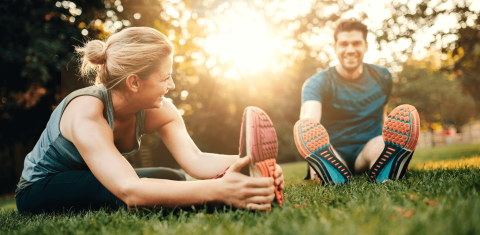 Ein Mann und eine Frau stretchen sich vor einem Lauf