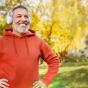 Ein Mann im roten Pullover hört mit seinem silbernen Kopfhörer Musik in einem Garten