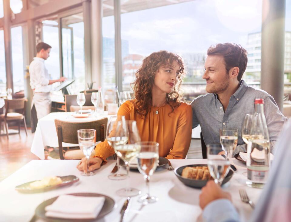 Paar sitzt romantisch im Restaurant bei Wein und Wasser und schaut sich an.